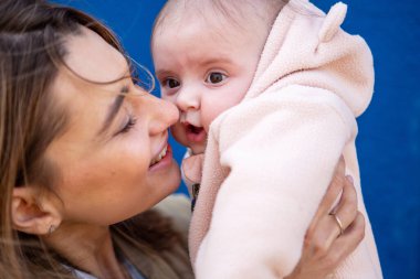 Sevgi dolu bir annenin bebeğine pembe bir elbise giydirmesi.