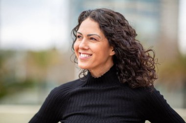 Kıvırcık bakışlı, kendinden emin, gülümseyen kadın portresi