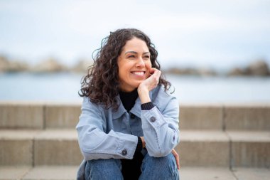 Gülümseyen kadın, açık hava merdivenlerinde oturuyor.