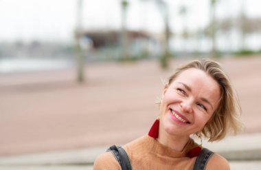 Gülümseyen orta yaşlı sarışın bir kadın gözlerini kaçırıyor.