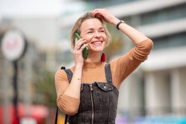 Neşeli kadın şehir dışında cep telefonuyla sohbet etmekten hoşlanıyor.