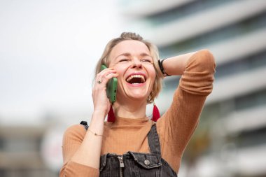 Gülen kadın şehir dışında cep telefonuyla konuşmaktan hoşlanıyor.
