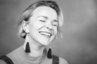 Siyah ve beyaz, gözleri kapalı gülen bir kadının yakın plan portresi.