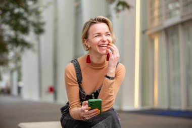 Şehrin dışında oturan neşeli kadın iyon elini tutuyor.