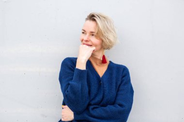 Mavi hırkalı şık beyaz kadın eli çenesine değmiş özenle gülümsüyor.