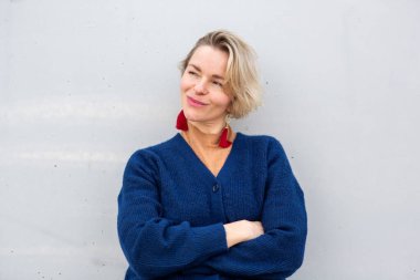 Kısa sarı saçlı, kollarını kavuşturmuş, özgüvenle gülümseyen oyuncu beyaz kadın.