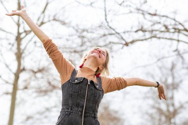Dışarıda kolları havada mutlu bir kadın bekliyor.