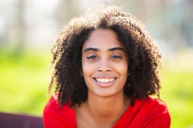 Kıvırcık saçlı, sıradan ve doğal ifadeli genç siyahi kadının yakın çekimi..