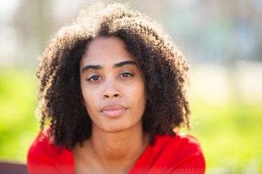 Açık havada kıvırcık saçlı genç siyah kadın, ılık doğal ışık..