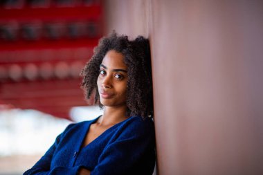 Güzel siyah kadın duvara yaslanıyor.