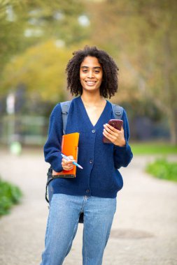 Dizin ve akıllı telefonu açık havada tutan kendinden emin bir öğrenci.