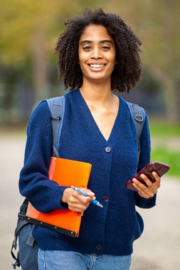 Telefon ve klasörle gülümseyen öğrencinin portresi