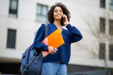 Dosyasıyla ve telefonuyla gülümseyen kendine güvenen zenci kadın.