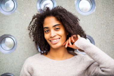 Dışarıda gülümseyen kadın duvara yaslanıyor.