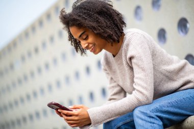 Cep telefonunda gülümseyen genç bir kadın.