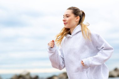 Kapüşonlu genç bir kadın dışarıda koşuyor.