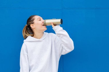 Mavi duvarın karşısında kahve içen kadın.