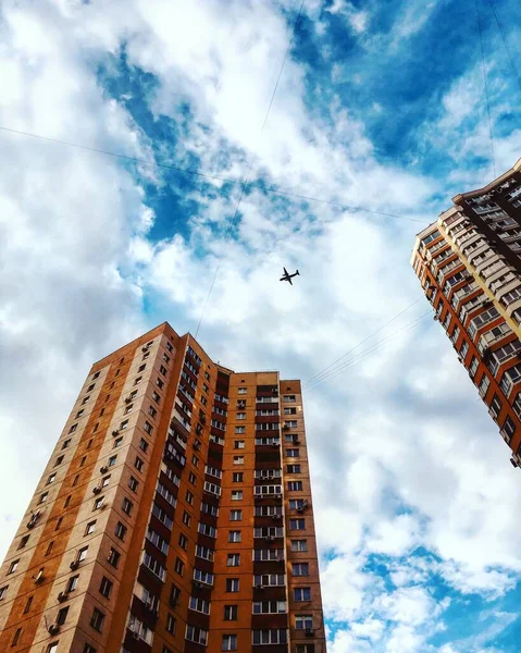 Arka planda mavi gökyüzü olan bir metropoldeki binaların üzerinde uçan bir uçağın hava görüntüsü. Havayolu. Huzurlu Kyiv Ukrayna. dikey resim