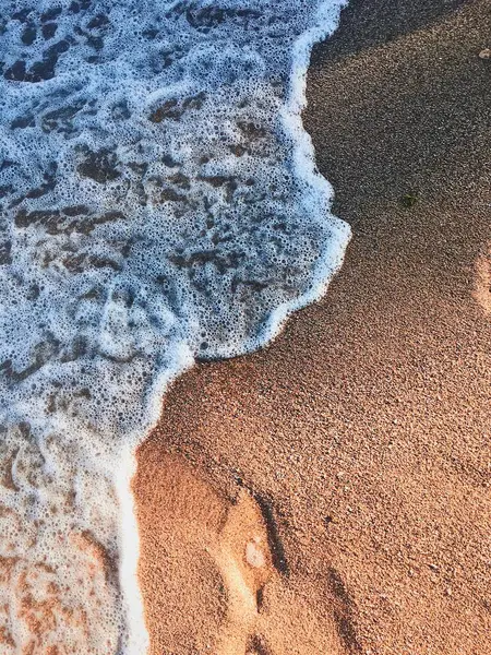 Kumlu bir sahilde denizin mavi köpük dalgası. Geçmişi. Seçici odaklanma. Turizm. Dikey resim