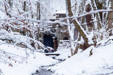 Kış Ormanı Akıntısı. Kar ve Akıntılı Kış Ormanı Sahnesi. Soğuk berrak su akıntısı. Kar yığınları ve orman ağaçlarıyla kış manzarası. Kış. Karlı Orman. 