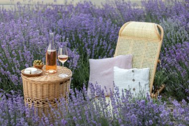 Lavanta tarlasında bir bardak beyaz şarap. Arka planda mor çiçekler