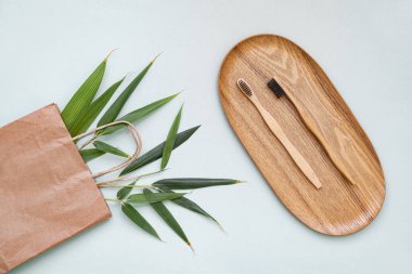 Bambu diş fırçası ve eco çantası mavi arka planda fotokopi alanı olan bir masada. Düz yaprak ve bambu yapraklarının şekillendirilmiş bileşimi