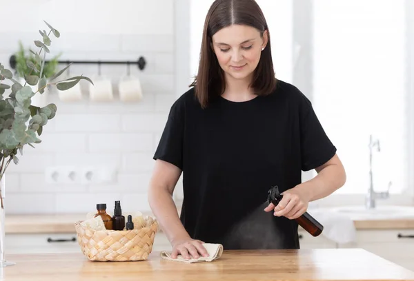 Young woman cleans the kitchen with eco products