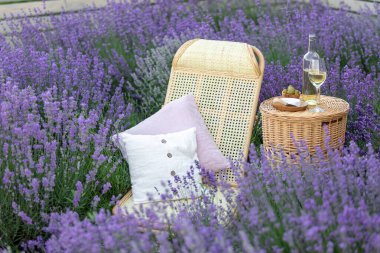 Lavanta tarlasında bir bardak beyaz şarap. Arka planda mor çiçekler