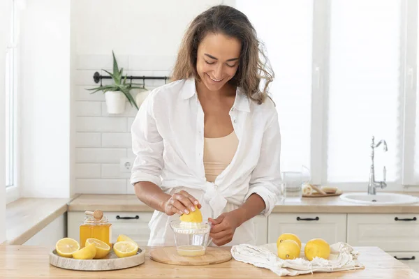 Young woman cutting lemon on wooden board. Preparation of fresh emonade. Lavender and lemon