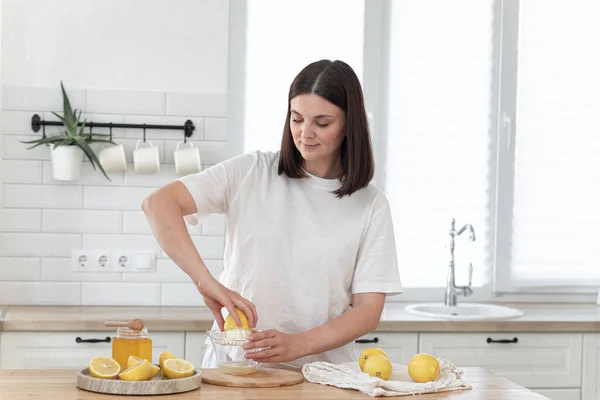 Young woman cutting lemon on wooden board. Preparation of fresh emonade. Lavender and lemon
