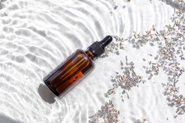 Bir şişe kehribar lavanta yağı. Düz konsept. Su dalgaları ile hafif arkaplan