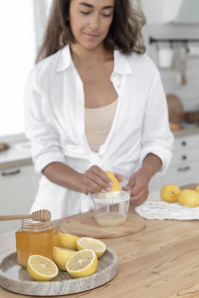 stock image Young woman cutting lemon on wooden board. Preparation of fresh emonade. Lavender and lemon