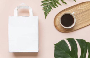 Poşetli ve tropikal yapraklı düz konsept. Sade kahve ile zarif bir kompozisyon.