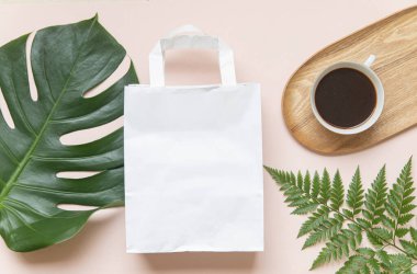 Poşetli ve tropikal yapraklı düz konsept. Sade kahve ile zarif bir kompozisyon.