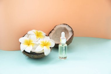 Hindistan cevizi yağı ve çiçek masanın üstünde pastel arka planda fotokopi alanı var. Düz zeminin tropikal arkaplan ile biçimlendirilmiş bileşimi