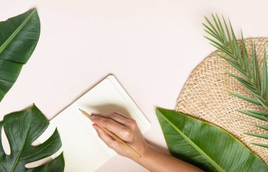 Tropik çalışma alanı konsepti. Not defteri ve tropik palmiye yaprakları. Model sunum çalışma yeri