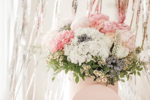 Pembe bir kutuda zarif bir buket gül, şakayık ve papatya. Işıkla dolu bir pencere tarafından güzelce düzenlenmiş ve yerleştirilmiş. Yüksek kalite fotoğraf. Doğum günleri ve düğünler için harika bir hediye.