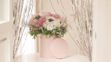 Pembe bir kutuda zarif bir buket gül, şakayık ve papatya. Işıkla dolu bir pencere tarafından güzelce düzenlenmiş ve yerleştirilmiş. Yüksek kalite fotoğraf. Doğum günleri ve düğünler için harika bir hediye.