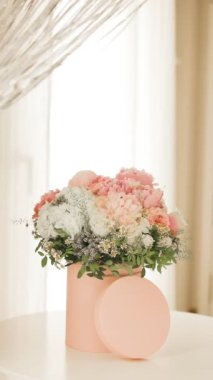 Pembe bir kutuda zarif bir buket gül, şakayık ve papatya. Işıkla dolu bir pencere tarafından güzelce düzenlenmiş ve yerleştirilmiş. Yüksek kalite fotoğraf. Doğum günleri ve düğünler için harika bir hediye.