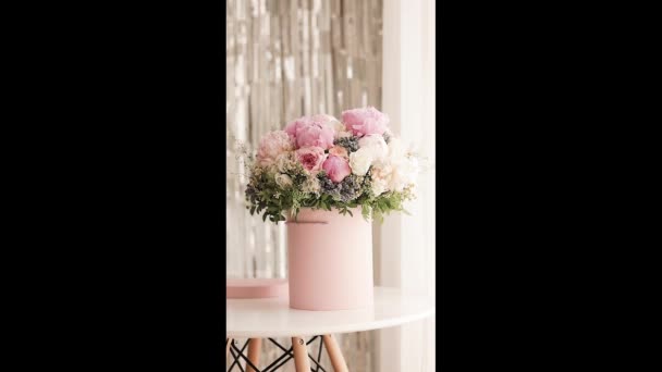 一束淡淡的玫瑰 牡丹和雏菊 装在粉红的盒子里 布置精美 放在布满灯光的窗前 高质量的照片 为生日 婚礼准备完美的礼物 — 图库视频影像