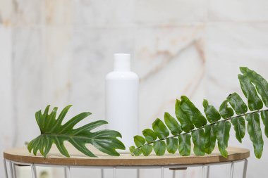 Beyaz şişe ve tropik arka planda palmiye yapraklarıyla cilt bakımı kavramı