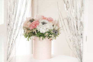 Pembe bir kutuda zarif bir buket gül, şakayık ve papatya. Işıkla dolu bir pencere tarafından güzelce düzenlenmiş ve yerleştirilmiş. Yüksek kalite fotoğraf. Doğum günleri ve düğünler için harika bir hediye.