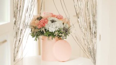 Pembe bir kutuda zarif bir buket gül, şakayık ve papatya. Işıkla dolu bir pencere tarafından güzelce düzenlenmiş ve yerleştirilmiş. Yüksek kalite fotoğraf. Doğum günleri ve düğünler için harika bir hediye.