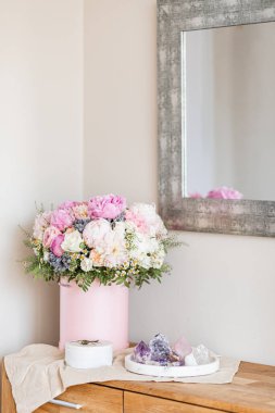 Pembe bir kutuda zarif bir buket gül, şakayık ve papatya. Işıkla dolu bir pencere tarafından güzelce düzenlenmiş ve yerleştirilmiş. Yüksek kalite fotoğraf. Doğum günleri ve düğünler için harika bir hediye.