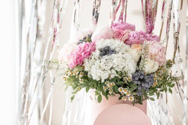 Pembe bir kutuda zarif bir buket gül, şakayık ve papatya. Işıkla dolu bir pencere tarafından güzelce düzenlenmiş ve yerleştirilmiş. Yüksek kalite fotoğraf. Doğum günleri ve düğünler için harika bir hediye.