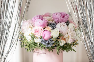 Pembe bir kutuda zarif bir buket gül, şakayık ve papatya. Işıkla dolu bir pencere tarafından güzelce düzenlenmiş ve yerleştirilmiş. Yüksek kalite fotoğraf. Doğum günleri ve düğünler için harika bir hediye.