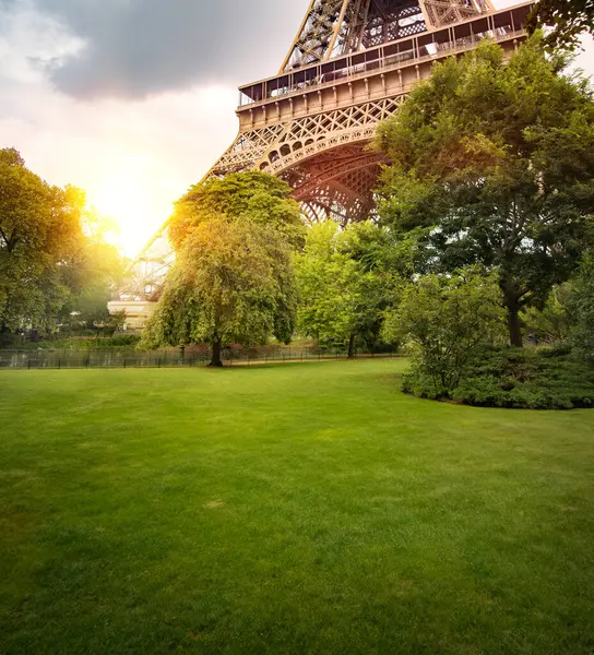局部视图的埃菲尔铁塔与太阳光线通过在公园里的绿树 — 图库照片#