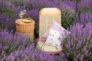 Lavanta tarlasında bir bardak beyaz şarap. Arka planda mor çiçekler