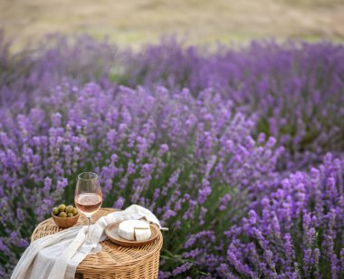Lavanta tarlasında bir bardak beyaz şarap. Arka planda mor çiçekler