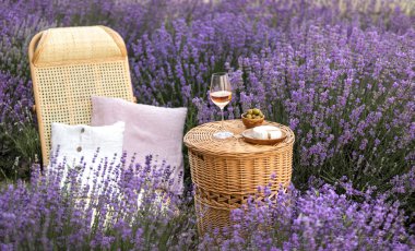 Lavanta tarlasında bir bardak beyaz şarap. Arka planda mor çiçekler